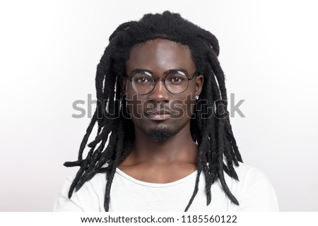 Handsome muscular black man with dreadlocks wearing glasses looking camera on white backgound Royalty-Free Stock Photo #1185560122
