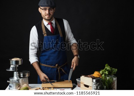 Pleased caucasian chef wearing spectacles and cap looking confidently at the camera and smiling representing professional approach to business