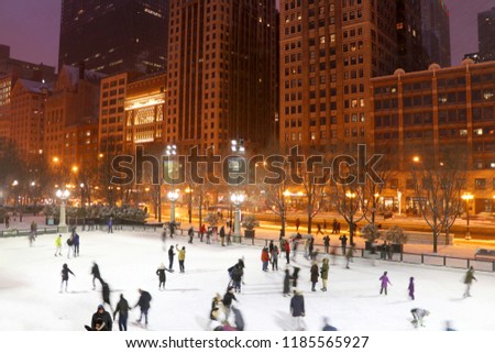 People in motion enjoying ice skating during beautiful winter night in Chicago downtown. Urban architecture background, big city life concept. Chicago, Illinois, Midwest USA.