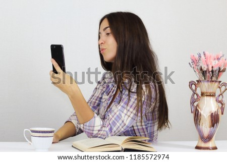 Young brunette woman talking on the phone and taking selfies