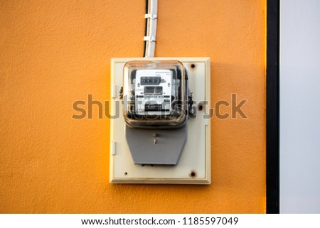 Electricity meter reading with copy space, Meter measuring instrument with sunset flare light, Watt-hour meter to measure electricity consumption use in home, Vintage orange background