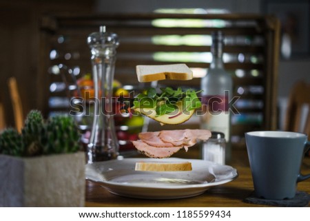 A picture of a "flying" sandwich with different layers of meat, salad, cheese and bread with an ambient background in a vertical layout