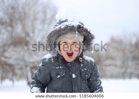 child in a warm jacket actively plays with snow and rejoices