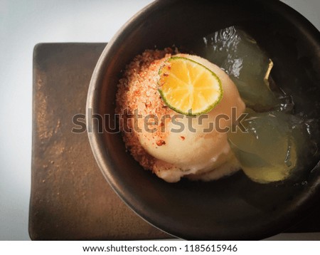 A glass cup of homemade  Kumquat  ( Kumquat  fruit) ice cream served with  chili salt and fruit jelly on table background, Thai dessert recipe, horizontal top view. Still life