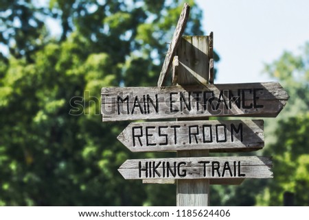 Hiking trail directional sign post with green trees and a blue sky in the background. Royalty-Free Stock Photo #1185624406