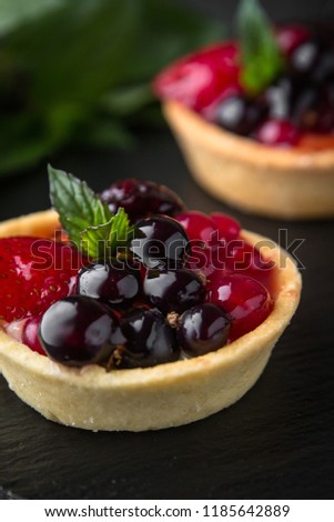 Pastry berry tart. Delicate crispy, crumbly dessert with black and red currants and mint. Assorted Confectionery Range.