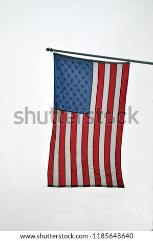American Flag hanging in Brooklyn New York City against a cloudy white sky