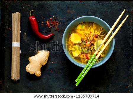 Light Soup in Asian Style with Buckwheat Noodles Soba and Salmon in the Blue Bowl with Chopsticks on black old metal background.Top view, copy space, flat lay.