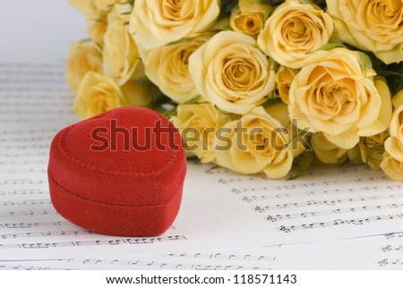 Yellow roses and a box holding wedding rings with musical background