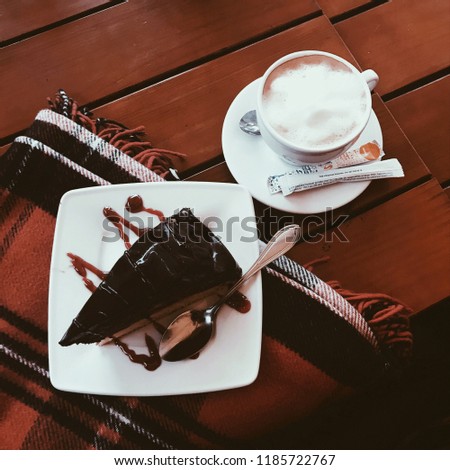 Coffee time. There is a plate with a chocolate cake and a cup of coffee in the picture. Photo from the top view.