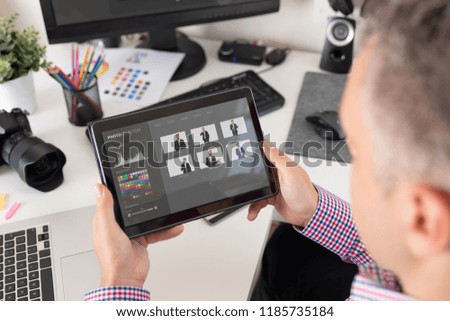Photographer looks at pictures on the tablet. Graphic designer at work.