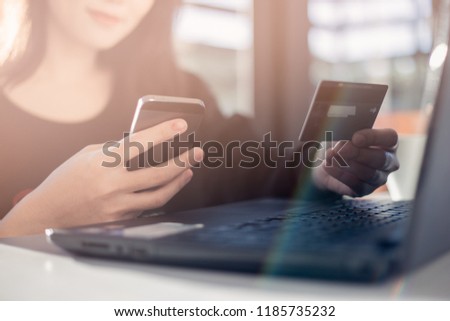 Close up hand holding credit card and using smart phone for shopping online. Holiday concept.