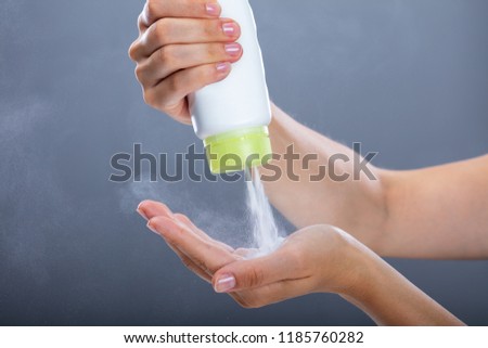 Woman's Hand Using Talcum Powder On Grey Background Royalty-Free Stock Photo #1185760282