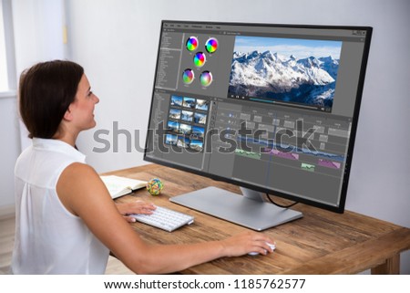 Female Editor Editing Video On Computer Over Wooden Desk