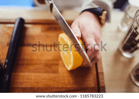 Party and holiday celebration concept. Bartender process of cooking sea buckthorn orange cocktail with cinnamon front view