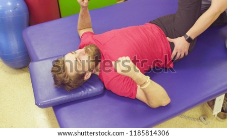 Doctor physical therapist doing leg exercises for young disabled man in a rehabilitation clinic.