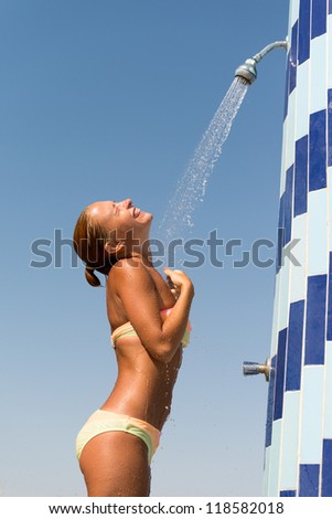 Sensous slim woman taking shower at the beach