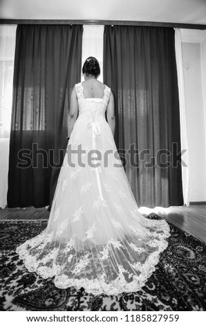 a black white picture of a young bride waiting for a groom, a bridelooking out the window and waiting for the groom, women in dress