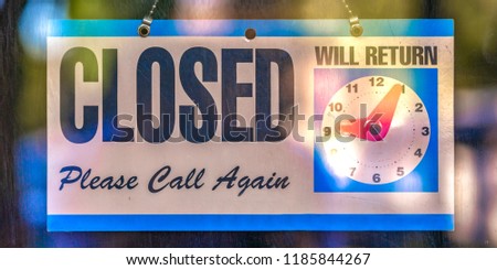 Closed sign with clock icon on a glass door