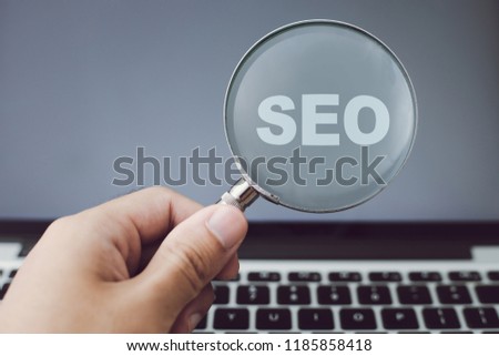 SEO concept on magnifying glass with the background of computer.