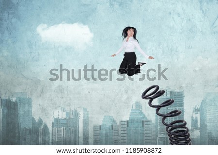 Picture of female entrepreneur looks happy while jumping by using a big spring