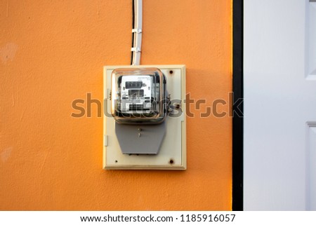 Electricity meter reading with copy space, Meter measuring instrument with sunset flare light, Watt-hour meter to measure electricity consumption use in home, Vintage orange background