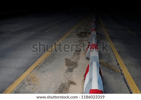 Barrier or red and white concrete apply on street in the dark.