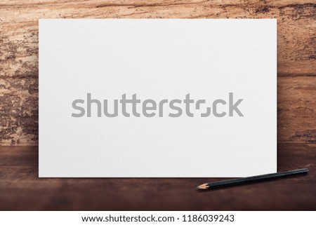 Blank banner white paper poster leaning at grunge wood wall on wooden floor in perspective room,Business mock up presentation.Template display of design or content
