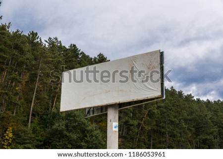 Empty commercial billboard, storm clouds on the background on early autumn day.
