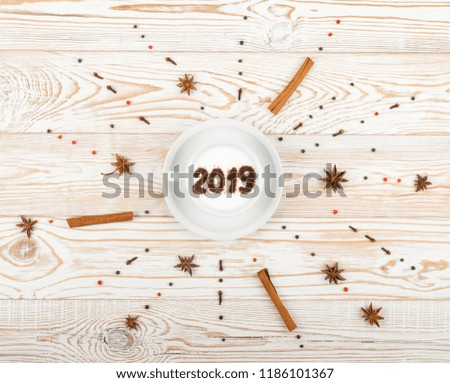New Year Numbers 2019 on Macchiato or Latte Cappuccino on Rustic Wooden Background. Hot Coffee Cup with Cream Milk Foam and Picture on a Festive Theme Top View