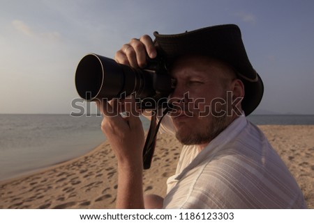 Photographer of a man in a pirate hat on the set on the beach near the sea