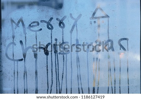 Texture of water droplets on clear window glass with Merry Christmas text