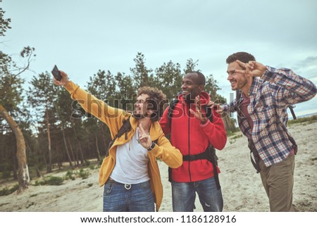 Say cheese. Happy travelers making selfie picture on the shore with forest on background