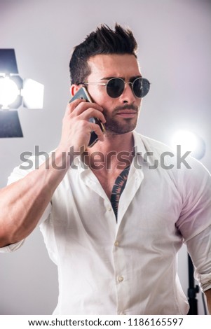 Attractive VIP man in studio with spotlights behind him, talking on cellphone