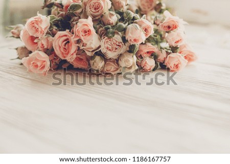 Pink small roses on wooden background in light, space for text. Floral greeting card mockup. Wedding invitation,happy mother day or Valentine day concept. Tender vintage image