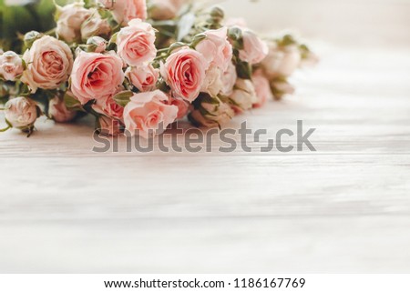 Pink small roses on wooden background in light, space for text. Floral greeting card mockup. Wedding invitation,happy mother day or Valentine day concept. Tender Flowers image