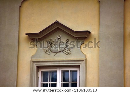 Ancient bas-reliefs on the Windows and walls of historical buildings. Architectural design elements from the past. Warsawa. Shield and spear on the crown of the window