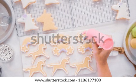Decorating unocrn shaped sugar cookies with royal icing for little girl birthday party.