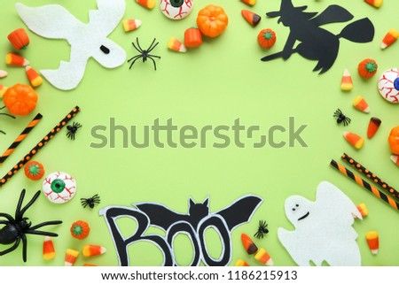 Halloween candies with decorations on green background