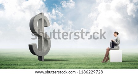 Elegant businesswoman with suitcase in hand sitting on white cube and big dollar sign