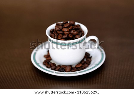 Cup of coffee with beans, on brown background.
