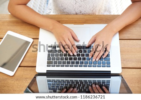 High angle shot of woman's hand while typing on laptop's keyboard.