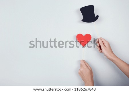 Female hands holding paper booth props on grey background