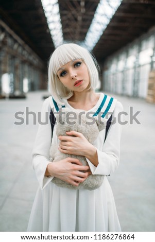 Anime style blonde girl hugs teddy bear