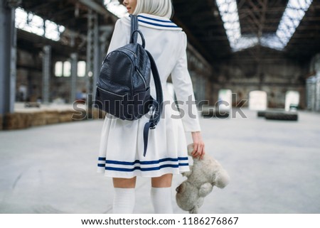 Anime style blonde woman looks at the toy bear
