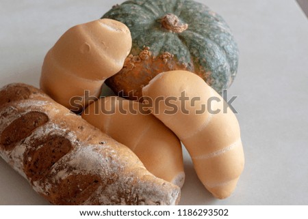 Bread and whole grain bread and autumn pumpkins on textured light background