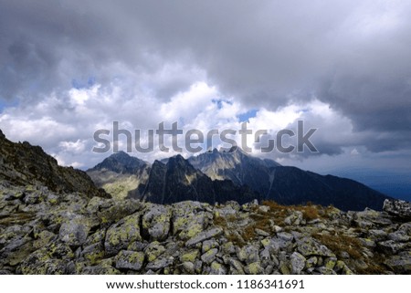 rocky sharp mountain tops in Tatra mountains in Slovakia with clouds and mist from above and rain clouds. Rysy mountain.