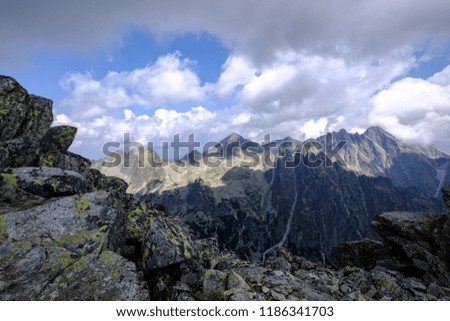 rocky sharp mountain tops in Tatra mountains in Slovakia with clouds and mist from above and rain clouds. Rysy mountain.