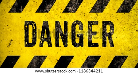 DANGER warning sign word text as stencil with yellow and black stripes painted over concrete wall cement texture wide banner background. Concept image for caution, dangerous area and hazard.
