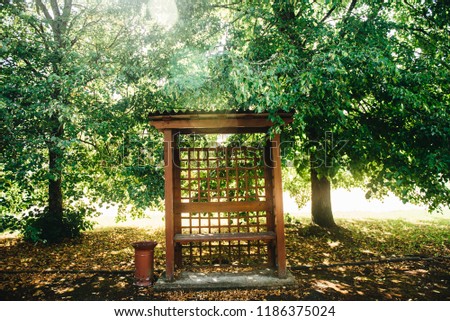 Wooden summerhouse in the park in the summer.. Outdoor wooden gazebo over summer landscape background